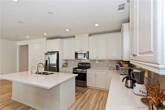 kitchen featuring stainless steel appliances, a kitchen island with sink, and white cabinets