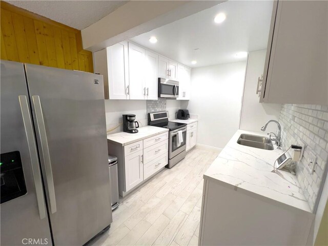 kitchen featuring white cabinetry, appliances with stainless steel finishes, sink, and backsplash