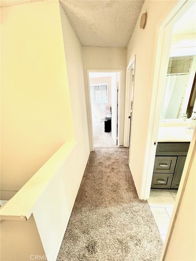 corridor with light colored carpet and a textured ceiling