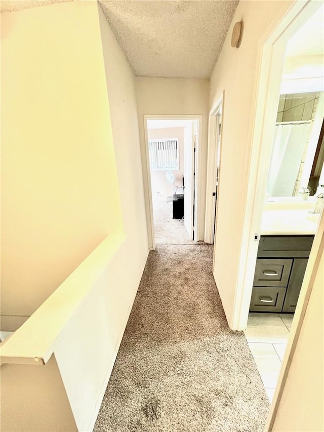 hall featuring light carpet and a textured ceiling