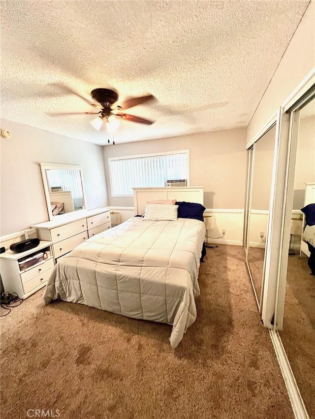 bedroom featuring multiple closets, ceiling fan, carpet, and a textured ceiling