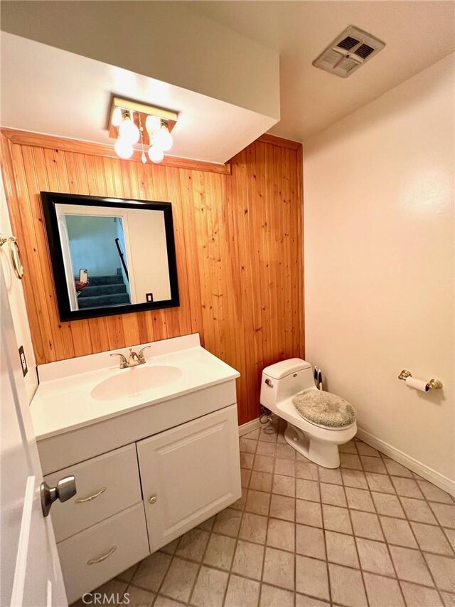 bathroom featuring wooden walls, vanity, toilet, and a chandelier