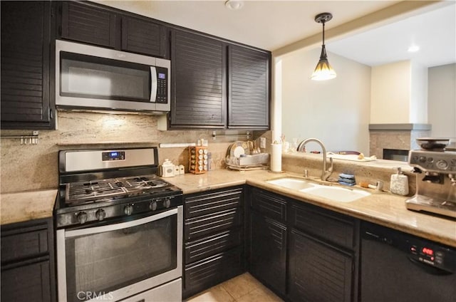 kitchen with light tile patterned floors, a sink, appliances with stainless steel finishes, decorative backsplash, and decorative light fixtures