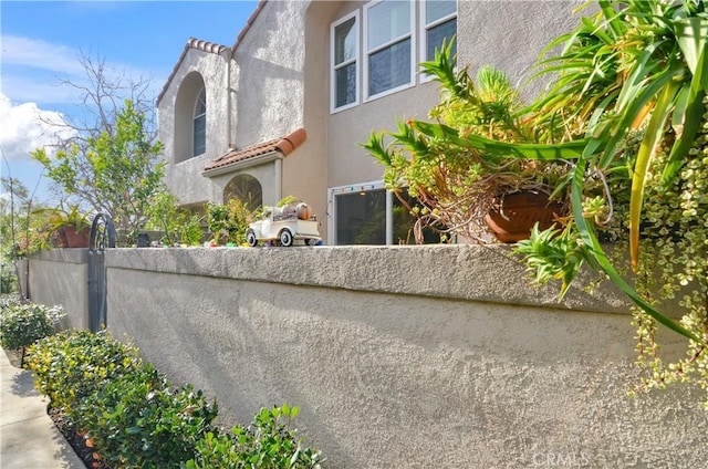 view of home's exterior with fence, a tiled roof, and stucco siding