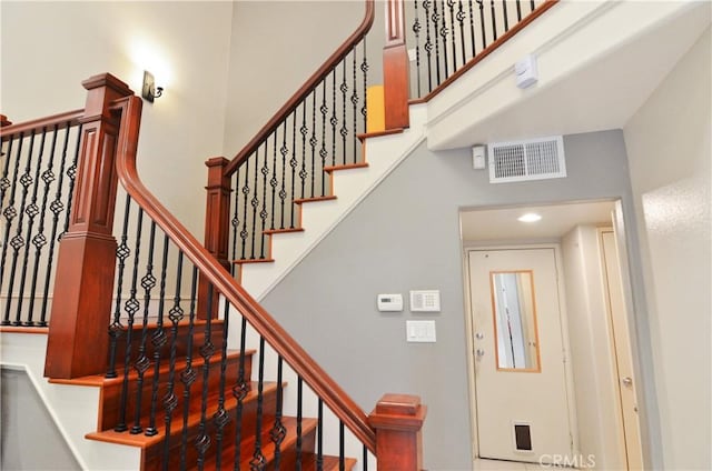 stairway with a towering ceiling and visible vents