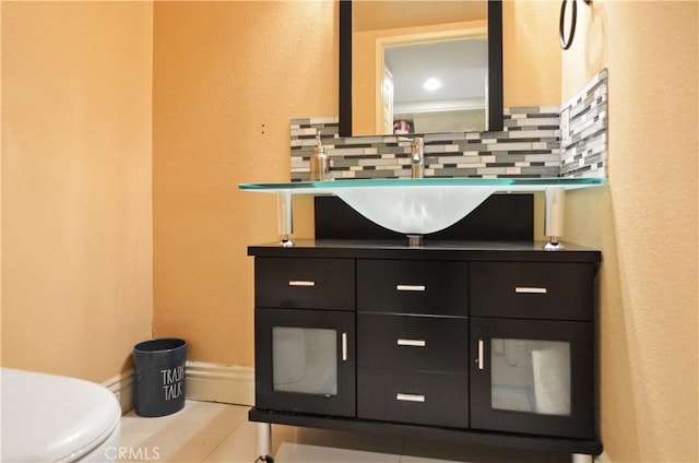 half bath with toilet, vanity, and decorative backsplash