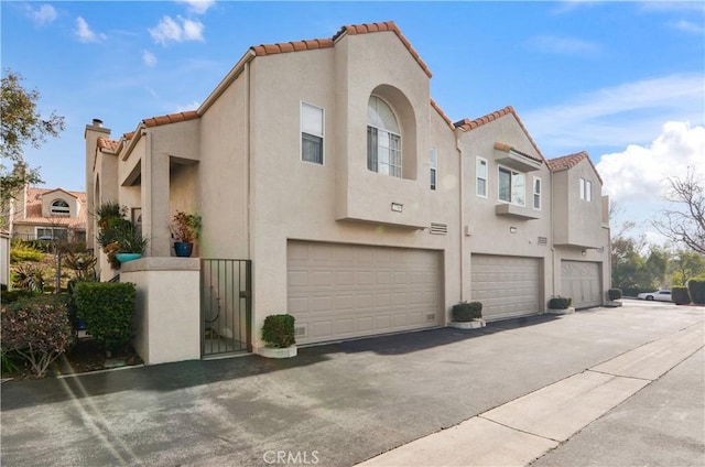 22307 Mission Cir, Chatsworth, CA 91311 - view of side of home featuring stucco siding, a tiled roof, a garage, a residential view, and a gate