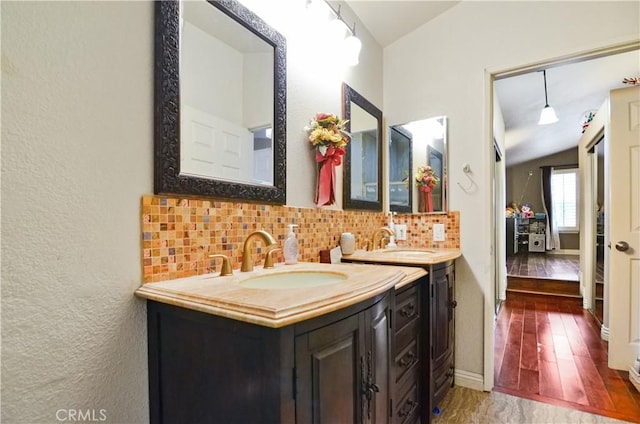 bathroom featuring tasteful backsplash, vaulted ceiling, hardwood / wood-style floors, and vanity