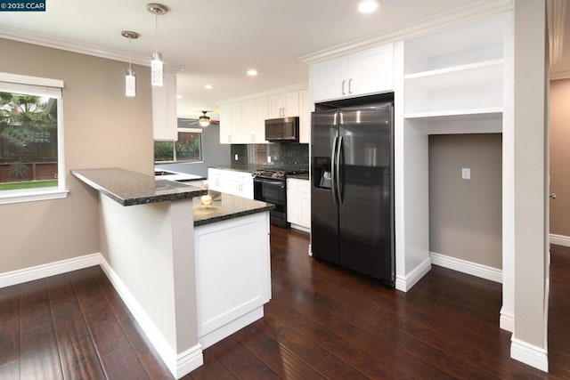 kitchen with appliances with stainless steel finishes, white cabinetry, decorative light fixtures, kitchen peninsula, and dark stone counters