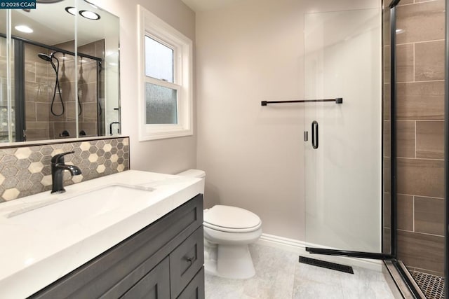 bathroom with vanity, toilet, an enclosed shower, and decorative backsplash