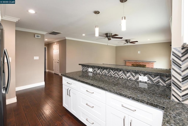 kitchen featuring pendant lighting, white cabinets, dark hardwood / wood-style flooring, dark stone counters, and crown molding