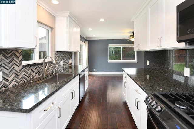 kitchen with white cabinetry, gas stove, sink, and dark stone countertops