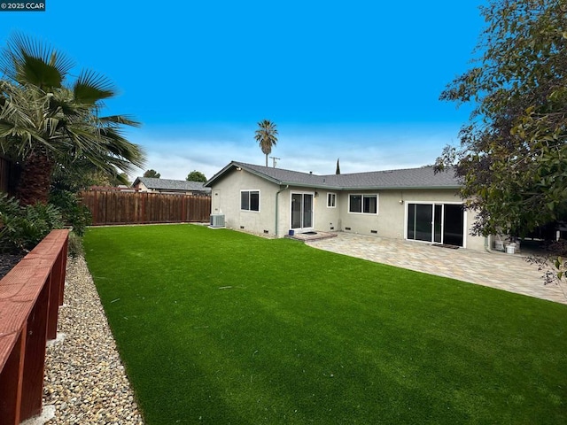 rear view of property featuring central AC unit, a patio area, and a lawn