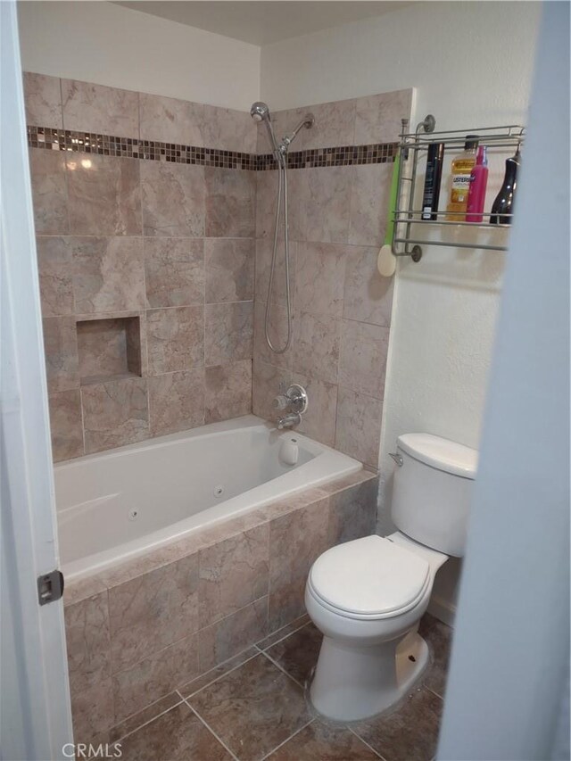 bathroom featuring tiled shower / bath combo, tile patterned floors, and toilet