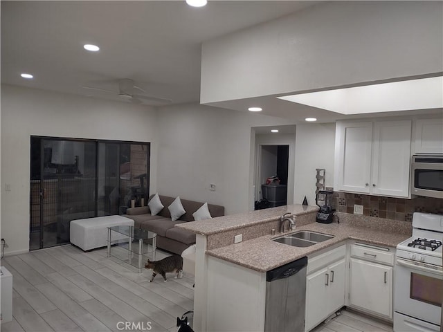 kitchen featuring sink, white cabinetry, stainless steel appliances, tasteful backsplash, and kitchen peninsula