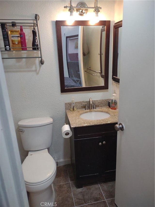 half bathroom with toilet, tile patterned flooring, baseboards, and vanity