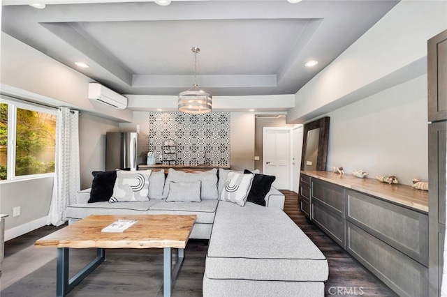 living room featuring dark wood-type flooring, a wall mounted air conditioner, and a tray ceiling