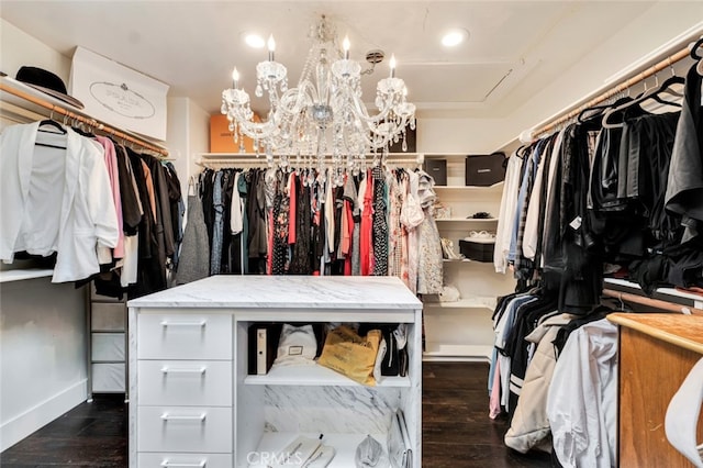 walk in closet featuring an inviting chandelier and dark hardwood / wood-style floors