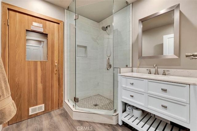 bathroom with hardwood / wood-style flooring, vanity, and walk in shower