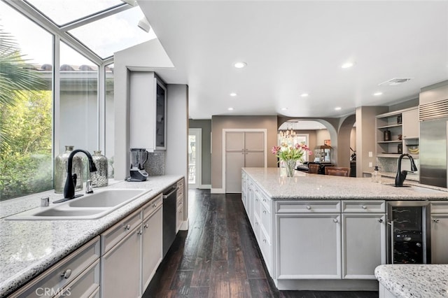 kitchen featuring sink, stainless steel appliances, light stone counters, wine cooler, and dark hardwood / wood-style flooring