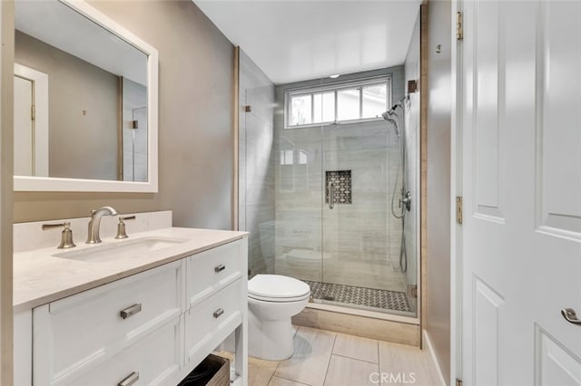 bathroom featuring a shower with door, vanity, and toilet