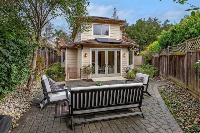 back of house with french doors, an outdoor hangout area, a patio area, and solar panels