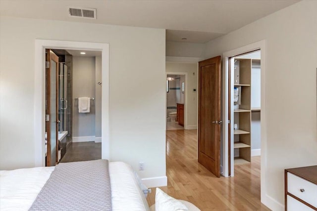 bedroom with ensuite bath, light hardwood / wood-style floors, and a closet