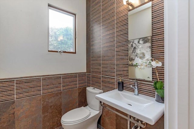 bathroom featuring toilet, sink, and tile walls