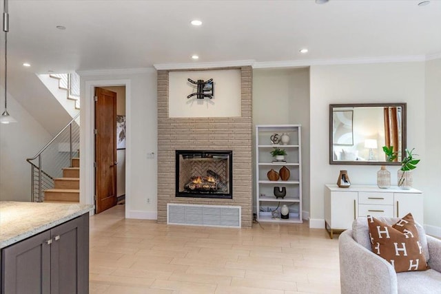 living room featuring crown molding, a large fireplace, and light hardwood / wood-style flooring