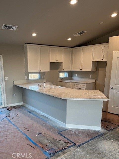 kitchen featuring white cabinetry, sink, kitchen peninsula, and vaulted ceiling