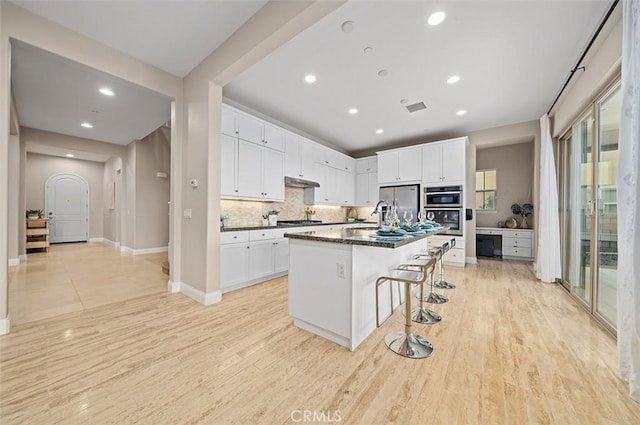 kitchen with appliances with stainless steel finishes, a breakfast bar, a center island with sink, and white cabinets