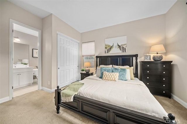 bedroom featuring light colored carpet, a closet, and ensuite bath