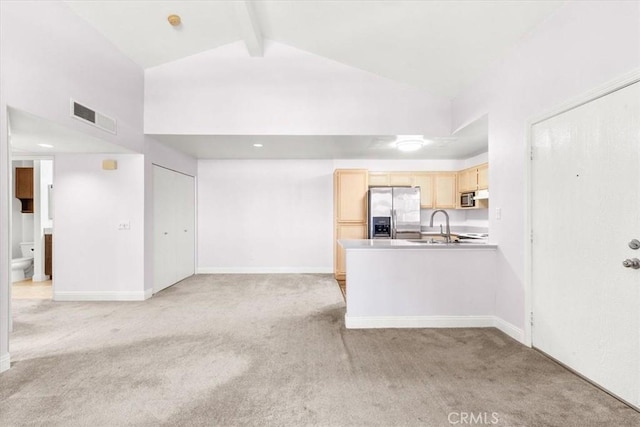 kitchen featuring high vaulted ceiling, light brown cabinetry, light colored carpet, stainless steel appliances, and beam ceiling