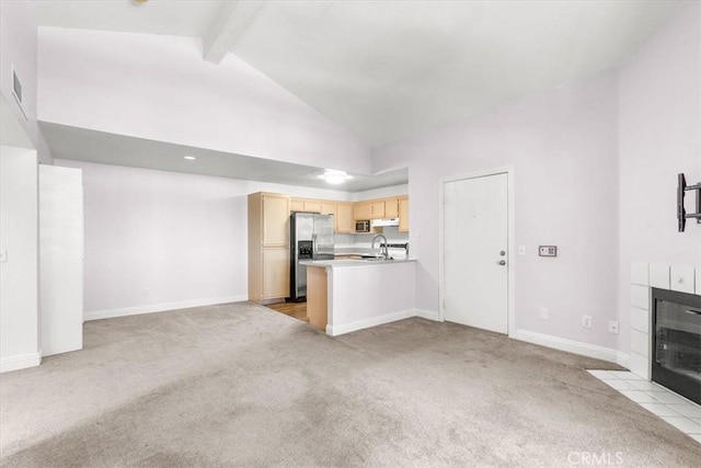 unfurnished living room with sink, beam ceiling, high vaulted ceiling, light carpet, and a fireplace