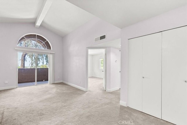 interior space with lofted ceiling with beams, light colored carpet, access to exterior, and a closet