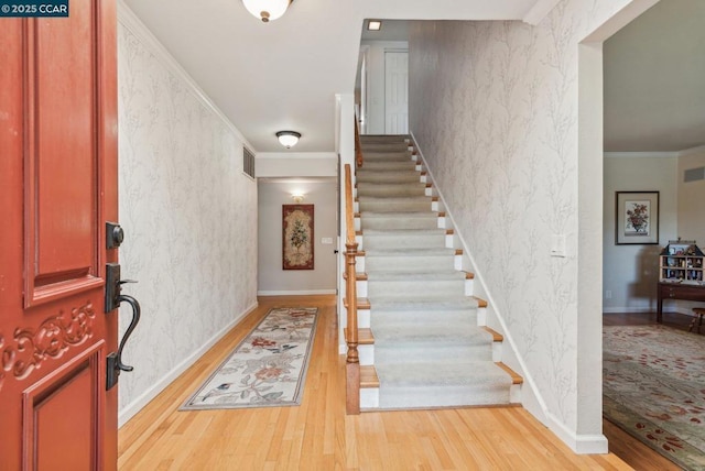 entrance foyer featuring ornamental molding and light hardwood / wood-style floors