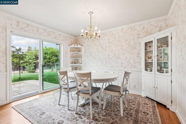 dining room featuring an inviting chandelier, light hardwood / wood-style flooring, and ornamental molding