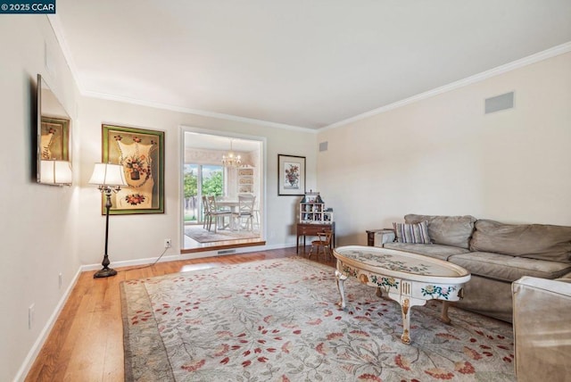 living room with an inviting chandelier, ornamental molding, and hardwood / wood-style floors