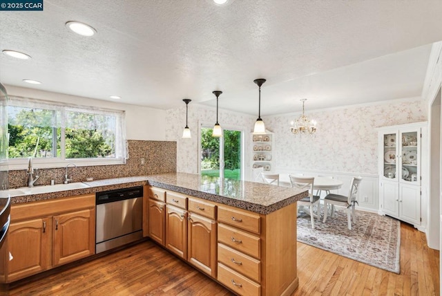 kitchen with sink, a wealth of natural light, stainless steel dishwasher, and kitchen peninsula