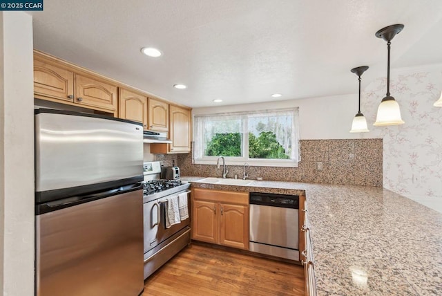 kitchen featuring sink, light hardwood / wood-style flooring, stainless steel appliances, tasteful backsplash, and decorative light fixtures