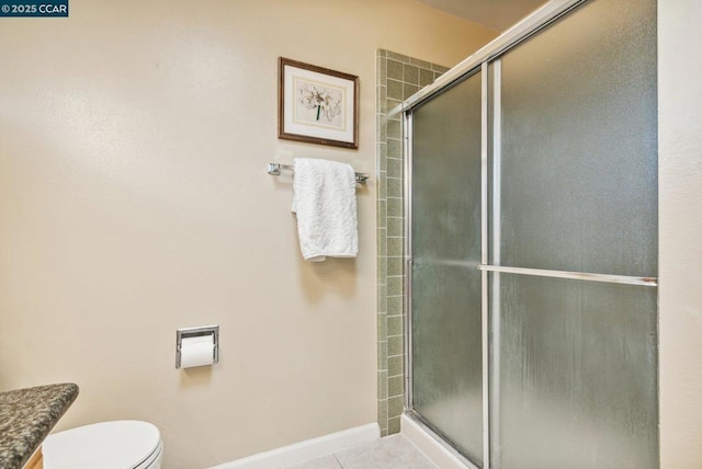 bathroom with tile patterned floors, a shower with door, and toilet