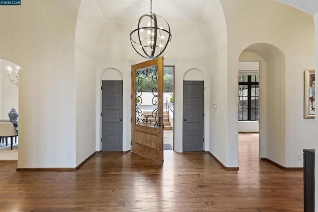 entryway featuring an inviting chandelier, dark hardwood / wood-style flooring, and high vaulted ceiling