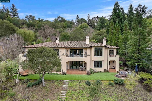 rear view of property with a balcony and a lawn