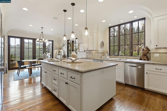 kitchen with pendant lighting, a kitchen island with sink, stainless steel dishwasher, and white cabinets