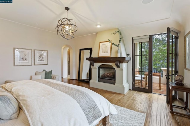 bedroom featuring hardwood / wood-style floors, access to exterior, and an inviting chandelier