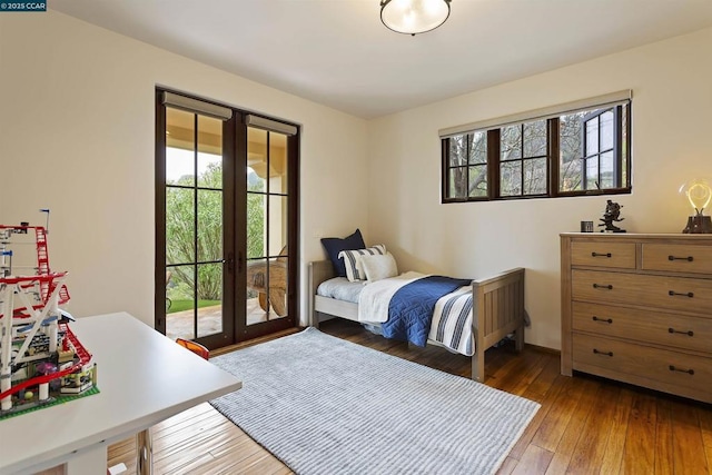 bedroom featuring multiple windows, access to exterior, dark hardwood / wood-style flooring, and french doors