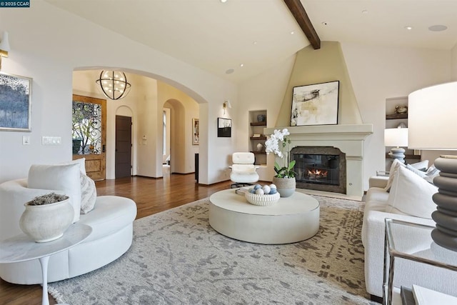 living room featuring high vaulted ceiling, a large fireplace, dark hardwood / wood-style flooring, a notable chandelier, and beam ceiling