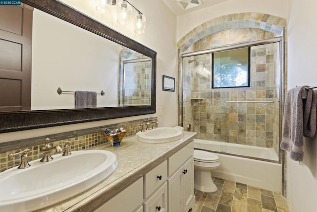 full bathroom featuring vanity, decorative backsplash, bath / shower combo with glass door, and toilet