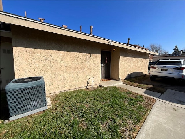 view of exterior entry with central AC and a yard