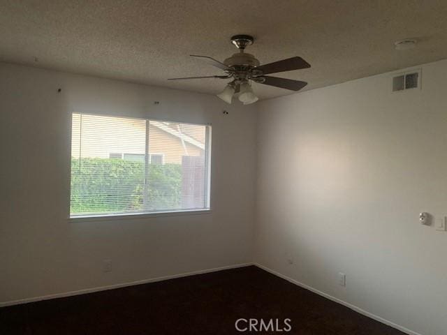 unfurnished room with ceiling fan and a textured ceiling